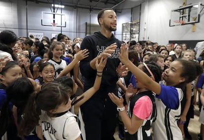 El jugador del Golden State Warriors Stephen Curry, junto a un grupo de niñas que practican baloncesto.