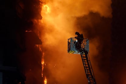 Un bombero trata de sofocar el edificio en llamas, en el barrio de Campanar de Valencia, este jueves.