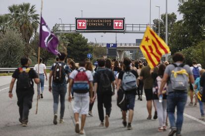 Viajeros y manifestantes caminan hacia el aeropuerto de El Prat, este lunes.