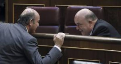 El ministro de Economía, Luis de Guindos (i), conversa con el diputado del PNV, Emilio Olabarría (d), durante el pleno de hoy en el Congreso de los Diputados.