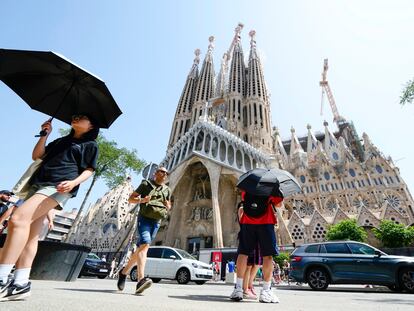 Una turista se protege del sol ante la Sagrada Familia de Barcelona este lunes, primer día de la ola de calor.