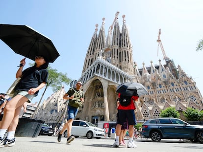 Una turista se protege del sol ante la Sagrada Familia de Barcelona este lunes, primer día de la ola de calor.