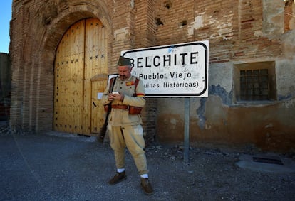 Un hombre disfrazado de soldado republicano mira el móvil mientas espera la llegada de turistas para ver Belchite viejo.