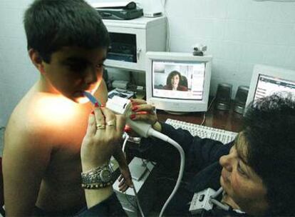 Una pediatra (en el monitor)  indica cómo  examinar a un niño durante un  ensayo de teleasistencia.