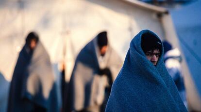 Tres immigrants coberts amb mantes esperen aquest dimecres un autobús al punt de registre de Presevo (Sèrbia).