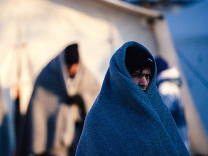 Tres immigrants coberts amb mantes esperen aquest dimecres un autobús al punt de registre de Presevo (Sèrbia).