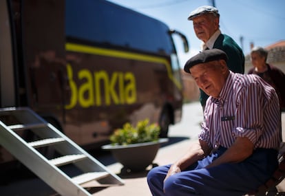 Varios habitantes de Corral de Ayllón (Segovia) hacen cola frente a una oficina móvil de Bankia.