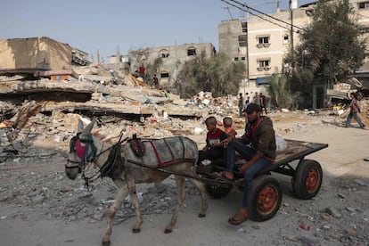 Un hombre y un niño pasan en un carro tirado por un burro frente a un edificio destruido tras los ataques israelíes en Rafah, en el sur de la franja de Gaza, este martes.