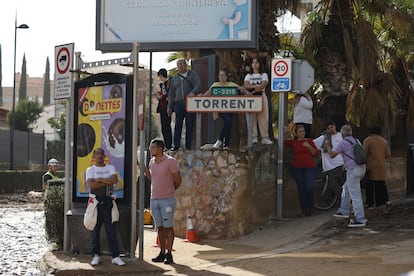 Vecinos de Torrent miran los trabajos de reparación del puente de la localidad, este jueves. 