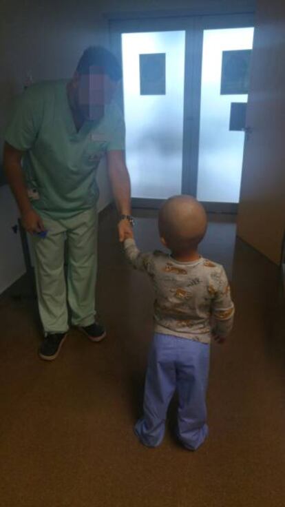 Un sanitario da la mano al niño en el Hospital Universitario de Torrevieja.