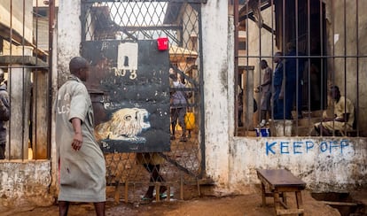 Un preso de Pademba frente a la puerta de entrada a uno de los patios, donde otros reos descansan sentados. Esta es la principal cárcel de Freetown, un centro con capacidad para 300 personas donde casi 2.000 hombres viven hacinados y en condiciones infrahumanas. La tuberculosis, la sarna o los insectos dominan un lugar con solo un grifo, unos cuantos retretes, un hospital sin medicinas y siete duchas. Alrededor de un 5% de los presos muere cada año.