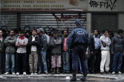 Un policía griego vigila a un grupo de inmigrantes durante una redada en Atenas.