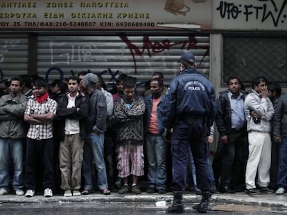 Un policía griego vigila a un grupo de inmigrantes durante una redada en Atenas.