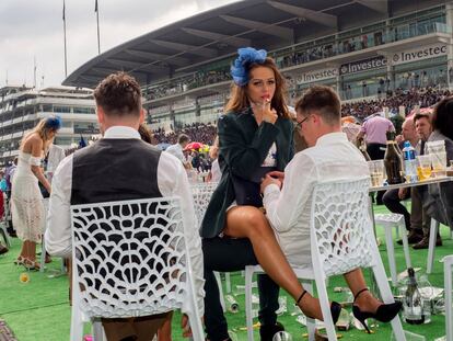 Una mujer fuma sentada sobre el regazo de un hombre en el Ladies’ Day (día de las mujeres) en las carreras de Epsom, que tradicionalmente se celebra el primer viernes de junio en el condado de Surrey.