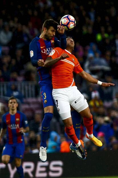 El defensa del Barcelona Gerard Piqué lucha por cabecear el balón con el delantero del Osasuna Sergio León.