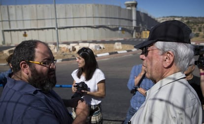 Vargas Llosa (d), junto a Yehuda Shaul ( Breaking the Silence), a la salida de Jerusalén, con el muro divisorio de fondo