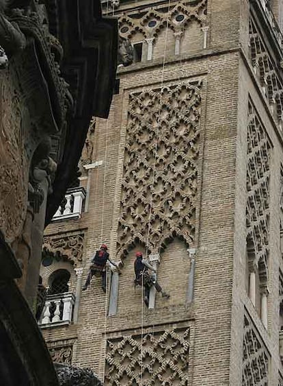 Dos obreros, ayer revisando la cara de la Giralda que mira a la plaza Virgen de los Reyes.