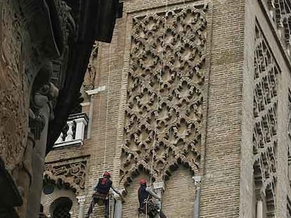 Dos obreros, ayer revisando la cara de la Giralda que mira a la plaza Virgen de los Reyes.