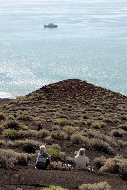 Dos turistas observan el buque del Instituto Español de Oceanografía (IEO) Ramón Margalef en la zona de la erupción volcánica submarina de La Restinga.