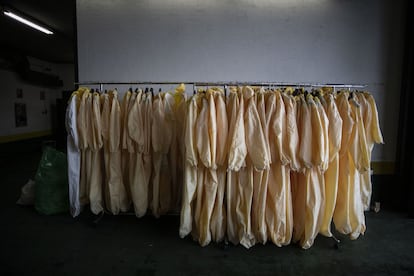 Percheros con trajes EPI (equipo de protección individual) en el garaje de los vehículos funerarios del Tanatorio M30 de Madrid.