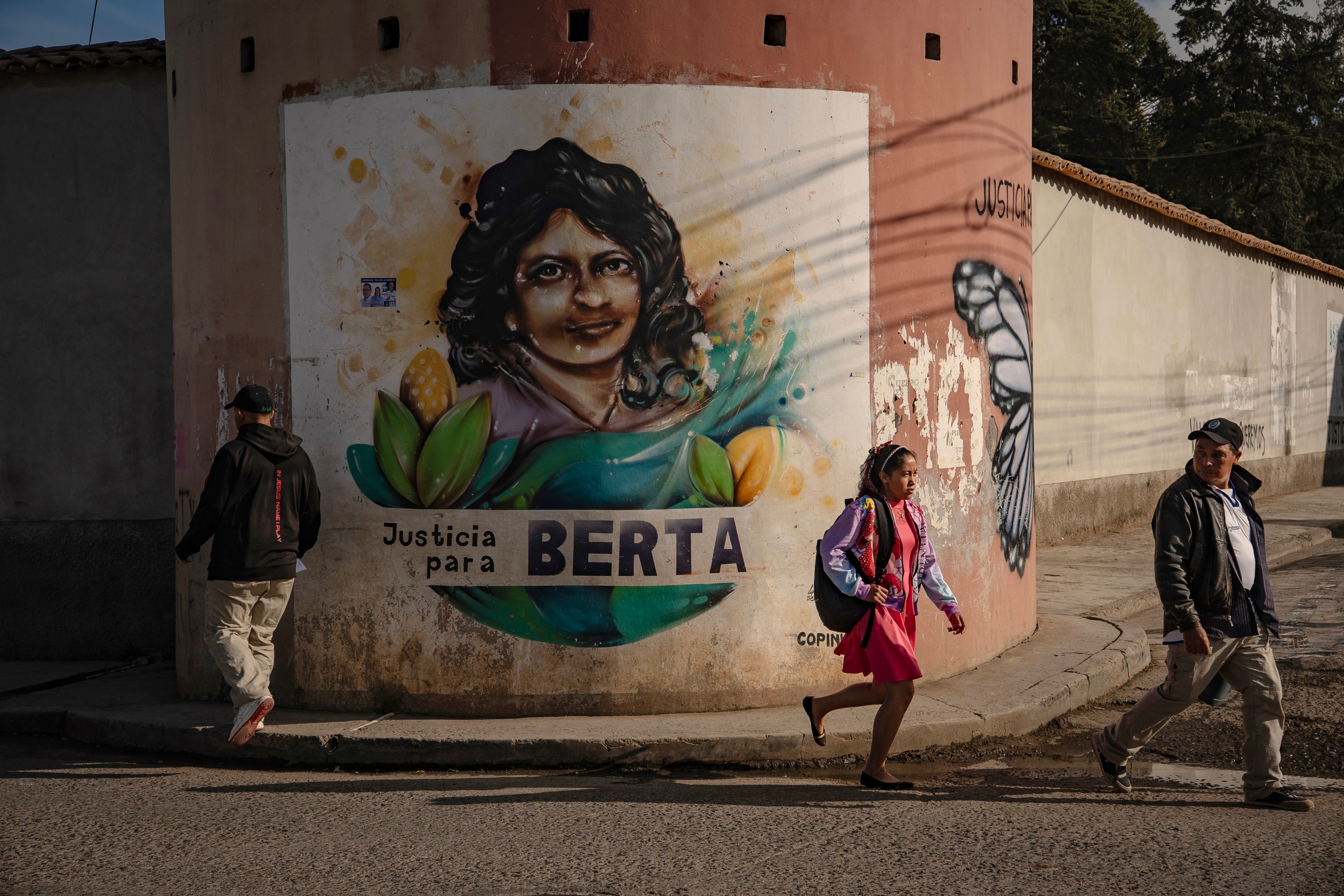 Personas caminan frente a un mural dedicado a Berta Cáceres, en la comunidad La Esperanza.