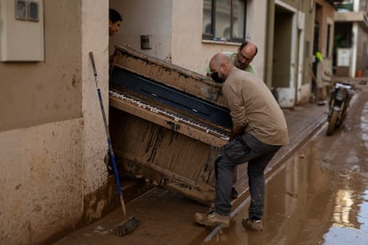 Lupe Murcia (izquierda) y Miguel Ramírez (detrás, a la derecha) retiran  de su casa un piano inutilizado por el agua el 5 de noviembre de 2024. El piano, que ahora lo utilizaba su hija, lo compró ella cuando era una estudiante. 


