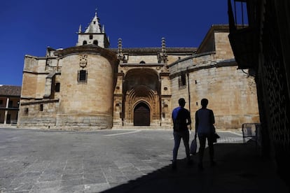 Dos personas caminan frente a la iglesia de Torrelaguna.