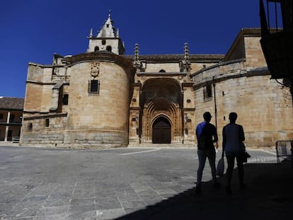 Dos personas caminan frente a la iglesia de Torrelaguna.