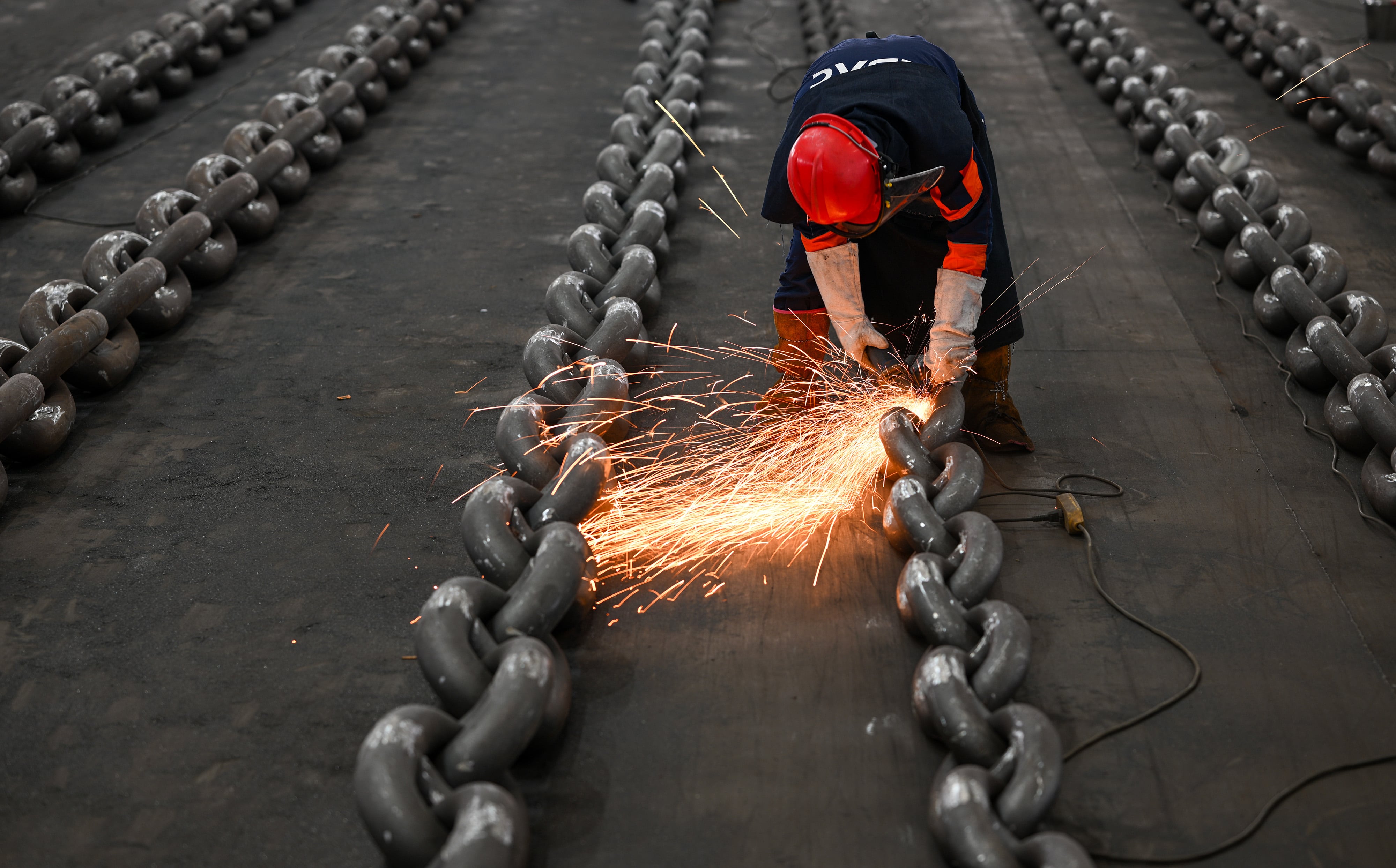 Un trabajador pule las cadenas de acero hechas para anclas de barcos en la provincia de Jiangsu, al este de China, el martes 21 de octubre de 2025.