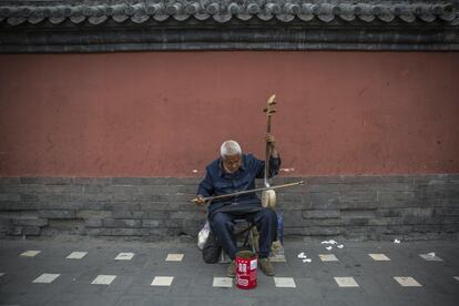 Un músico callejero invidente toca el leyquín, un instrumento musical tradicional chino, en una calle del barrio Hutong de Pekín, China.