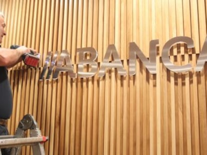 Un obrero coloca el nuevo logotipo en un edificio de la entidad en Santiago
