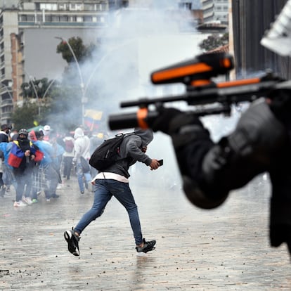 BOGOTA, COLOMBIA - MAY 05: A riot police officer shoots towards protesters at Bolivar Square during national strike on May 05, 2021 in Bogota, Colombia. Despite that the ruling party announced withdrawal of the unpopular bill for a tax reform and the resignation of the Minister of Finances, social unrest continues after a week. The United Nations human rights office (OHCHR) showed its concern and condemned the riot police repression. Ongoing protests take place in major cities since April 28. (Photo by Guillermo Legaria/Getty Images)