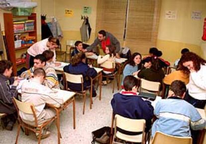 Monitores voluntarios ayudan a los niños a hacer sus deberes en el taller de Cruz Roja en Fuenlabrada.