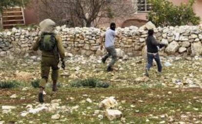 Un soldado israelí persigue a dos manifestantes palestinos durante una protesta contra el asentamiento judío de Qadomem, cerca de la ciudad cisjordana de Nablus. EFE/Archivo