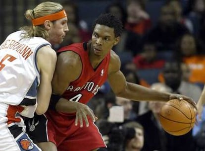 El jugador de los Raptors Chris Bosh (derecha) intenta deshacerse del argentino Walter Herrmann, de los Bobcats.