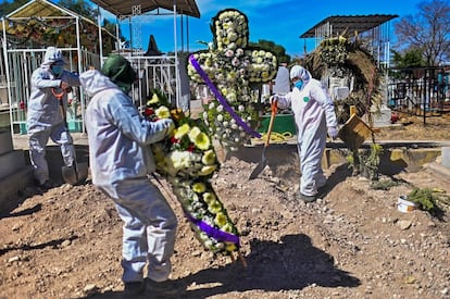 Un enterrador coloca flores sobre la tumba de una víctima de coronavirus, en el cementerio de Ecatepec (México).