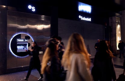 Varias personas pasan junto a una sucursal del Sabadell en Bilbao.