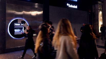 Varias personas pasan junto a una sucursal del Sabadell en Bilbao.