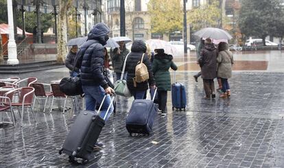 Turistas arrastran sus maletas por el centro de San Sebastián, este lunes. Se esperan chubascos generalizados, abundantes y con alguna tormenta ocasional en Galicia, Cantábrico y los Pirineos, que podrían ser localmente persistentes en el litoral cantábrico.