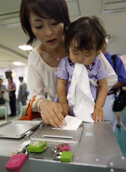 Una mujer con su hija vota en un colegio electoral de Tokio.