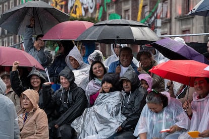 Asistentes al Grito de Independencia en el Zócalo se resguardan de la lluvia.