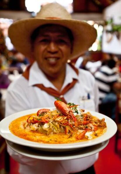 Un camarero de la picantería La Nueva Palomino con un plato de chupe de camarones.