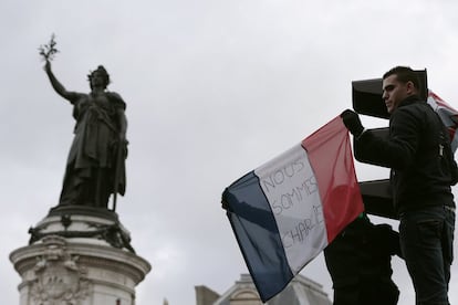 Um homem segura uma bandeira francesa com os dizeres "Nós somos Charlie".