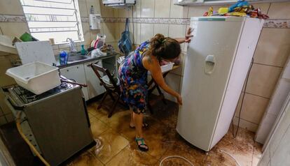 Una mujer limpia el lodo de su refrigerador después de que las lluvias inundaran su casa.