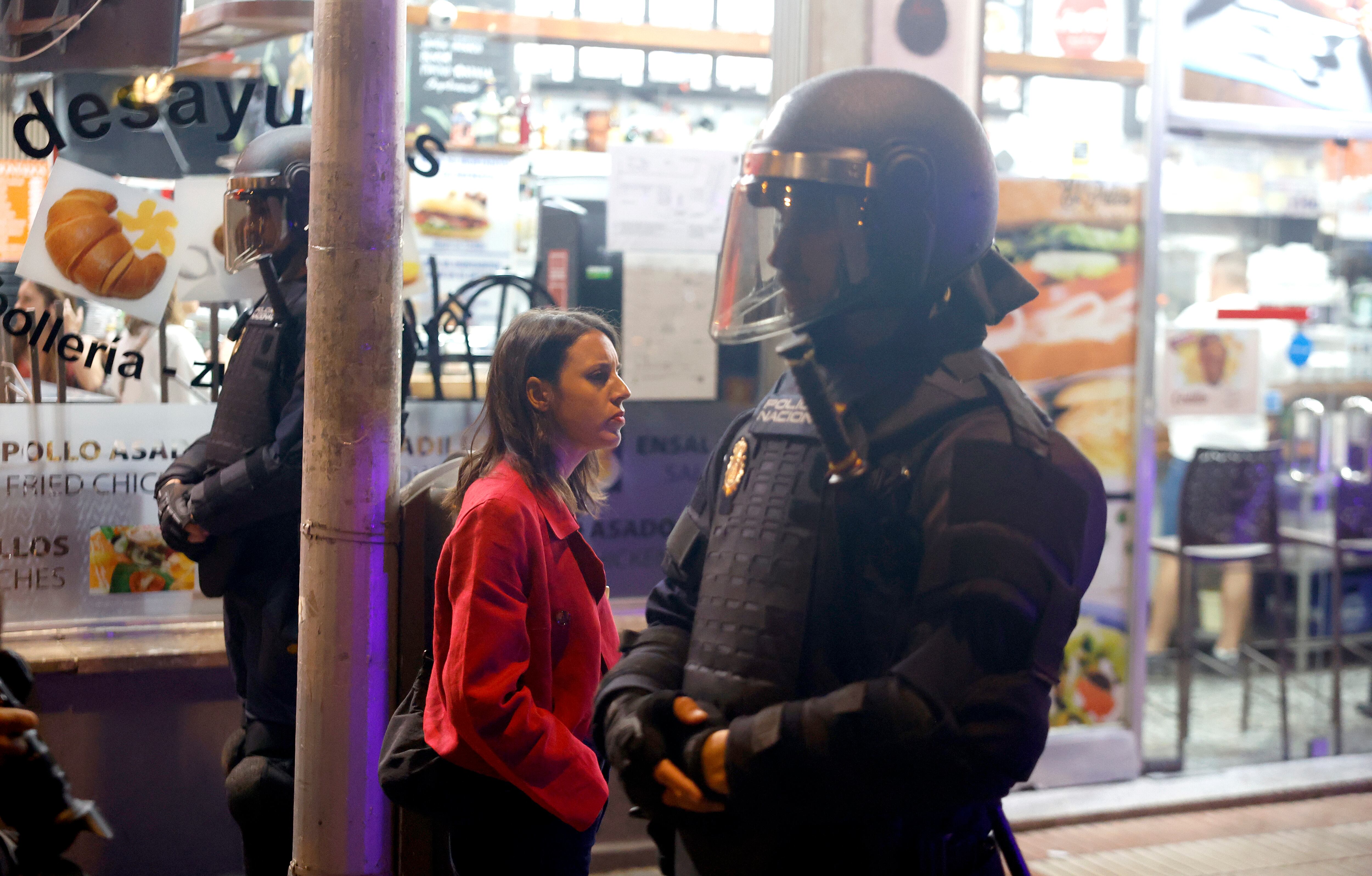 La eurodiputada Irene Montero pasa entre dos agentes antidisturbios frente al portal de la vivienda de Maricarmen.