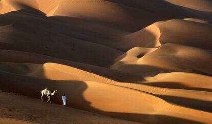 Un hombre pasea con un camello por el desierto de Liwa (Abu Dabi). 