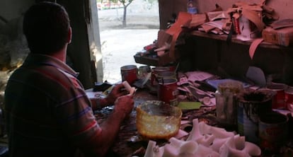A worker glues shoes together in an illegal workshop in his home.