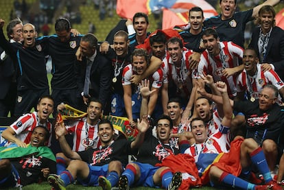 Los jugadores del Atlético posan en el césped con el trofeo, que suejeta Forlán y tapan Agüero y Jurado con sus brazos