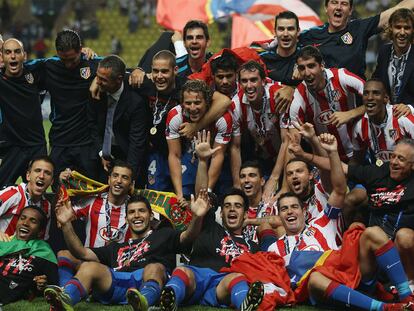 Los jugadores del Atlético posan en el césped con el trofeo, que suejeta Forlán y tapan Agüero y Jurado con sus brazos