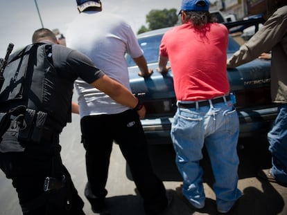 Un policía catea viajeros en un retén.